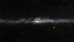 銀河系在繁星點點的宇宙背景下，呈現出發光的星雲和黑暗的塵埃帶。