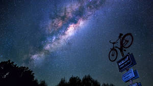 單車安裝在路標上，星空夜空下，銀河可見。 — 銀河系 壁紙