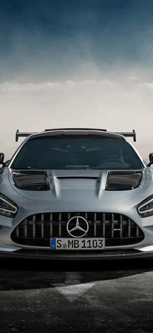 在暴風雨的天空下，潮濕道路上的銀色 Mercedes-AMG GT R 跑車。 — Galaxy M36 壁紙