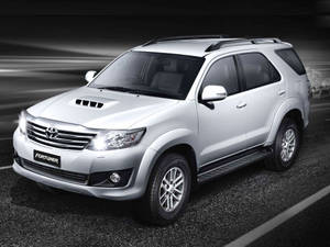 銀色豐田 Fortuner SUV 在黑暗的道路上行駛，帶有動態模糊效果。