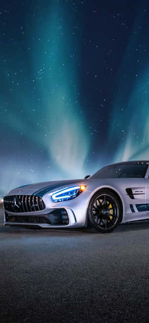 夜間在發光極光下的銀色跑車 — Galaxy M17e 壁紙