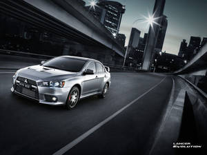 銀色三菱Lancer Evolution在黃昏時分在城市高速公路上疾馳。