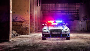 一輛警車在黑暗的廢棄倉庫內閃爍著燈光。