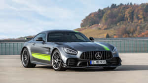 銀色 Mercedes-AMG GT R 帶有綠色賽車條紋，停在秋日山丘附近的戶外。