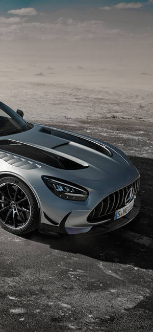 銀色 Mercedes-AMG GT R 跑車在龜裂的瀝青路上，天空多雲。