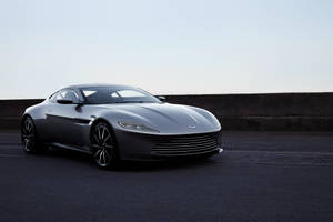 銀色Aston Martin跑車停泊在瀝青路上，靠近混凝土護欄。