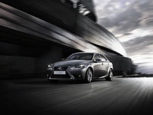 銀色 Lexus IS 300h 在現代混凝土天橋下疾馳，帶有動態模糊效果。