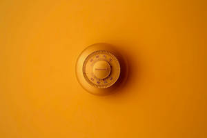 安裝在橙色牆壁上的Honeywell恆溫器。 — 簡約 壁紙