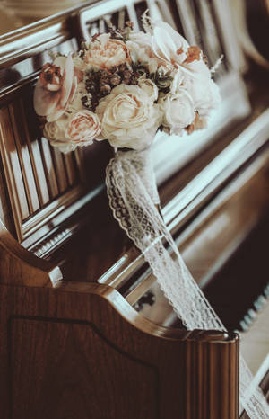 一個帶有蕾絲絲帶的婚禮花束放在木製教堂長椅上。