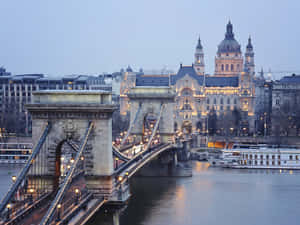 暮色中的多瑙河鏈橋，背景有燈火通明的建築 — 美景 壁紙