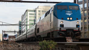 Amtrak火車在城市鐵路調車場中行駛，後面是高樓大廈。