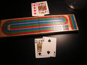 Cribbage 板同啤牌喺黑暗嘅枱上。