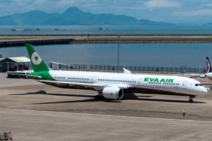長榮航空飛機在機場停機坪上，背景有山脈和海洋