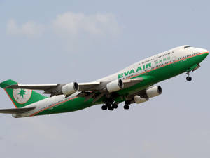 長榮航空波音747飛機在多雲天空下放下起落架降落。