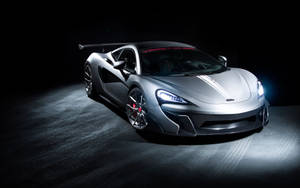 銀色McLaren跑車在黑暗的攝影棚燈光下帶有發光的車頭燈。 — 麥拿侖 GIF 壁紙