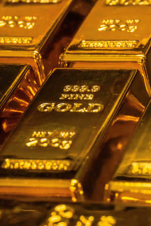 帶有雕刻標記的堆疊金條反射溫暖光線。 — 金色美學 GIF 壁紙