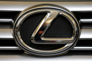 黑色穿孔背景的汽車格柵上的鍍鉻 Lexus 標誌。
