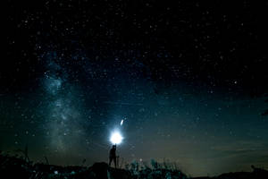 人在星空下手持電筒，銀河可見