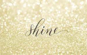 喺金色閃粉背景上以黑色草書寫嘅「shine」呢個詞。