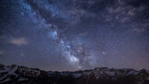 積雪的山脈在充滿活力的星空下，銀河清晰可見。
