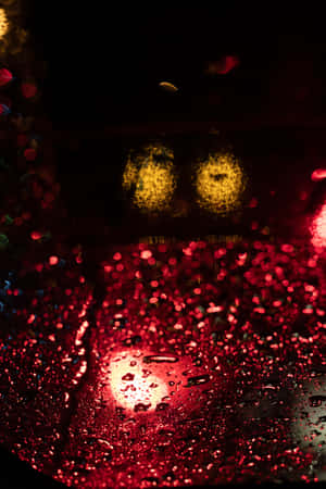 車窗上的雨滴反射出夜間發光的城市燈光。