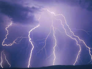 強烈的閃電劃過黑暗地平線上方暴風雨般的紫色天空。