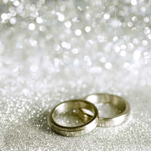 兩枚銀色結婚戒指在閃閃發光的銀色背景上。