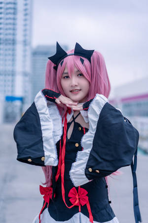 一位年輕女性穿著女僕角色扮演服，粉紅色頭髮和貓耳，在城市中對著鏡頭微笑。
