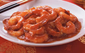 糖醋蝦菜餚，配上筷子，放在紅色圖案枱布上。 — 16:10 壁紙