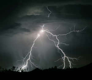 強烈的閃電照亮了黑暗山丘上方的暴風雨夜空。