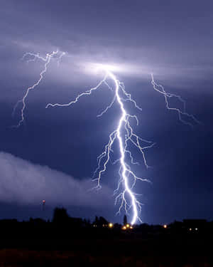 強大的閃電照亮了鄉村景觀上空的暴風雨之夜，遠處有燈光。