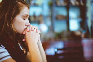 年輕女性在室內雙手合十靜默祈禱