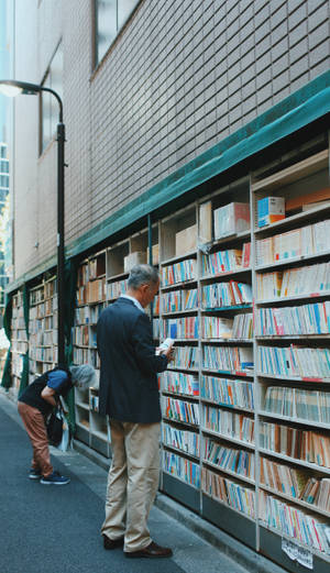 男士在城市小巷的戶外書架上瀏覽書籍