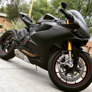啞光黑色杜卡迪 Panigale V4 摩托車，配備金色前叉和紅色點綴，停在戶外。