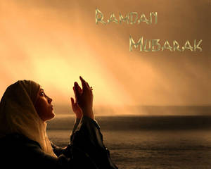戴頭巾的女性在日落時祈禱，帶有Ramadan Mubarak文字。