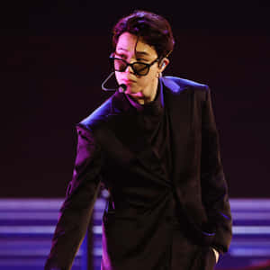 一位身穿黑色西裝和太陽眼鏡的歌手在燈光璀璨的舞台上表演。 — 啞光黑色 壁紙