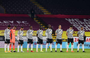 身穿間條球衣的足球員在夜間草地上排成一列。