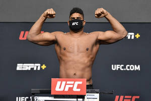 UFC拳手在稱重時彎曲手臂，戴著黑色口罩