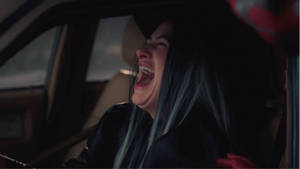 一位藍髮女性在車內開懷大笑。