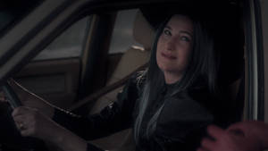 女性在黃昏時駕駛汽車，平靜微笑
