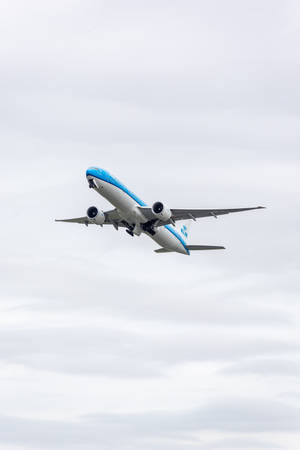KLM飛機穿過多雲天空爬升，起落架放下
