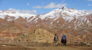 兩個人騎著馬走過沙漠山谷，背景是雪山。 — 山邊 壁紙