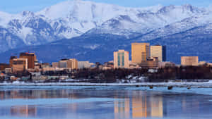 黎明時分冰水中反射出白雪覆蓋山脈的城市天際線。 — 城市景觀 壁紙