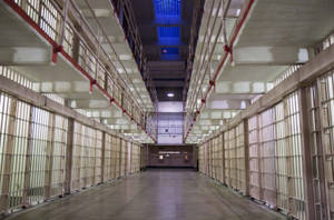 螢光燈下多層鐵欄的長長空蕩監獄走廊。