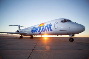 日出時 Allegiant 飛機在跑道上，金色光線反射在停機坪上。