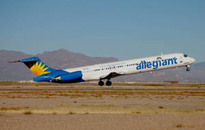 Allegiant Air 飛機從沙漠跑道起飛，背景有山脈。