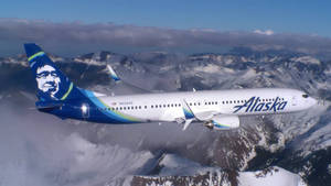 阿拉斯加航空飛機在晴朗日子飛越積雪山脈。