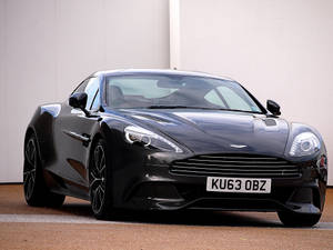 黑色Aston Martin跑車停在白色牆壁前。