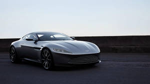 銀色Aston Martin跑車停泊在道路旁混凝土護欄邊。