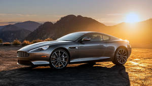 銀色Aston Martin跑車停在日落時分的山路上。